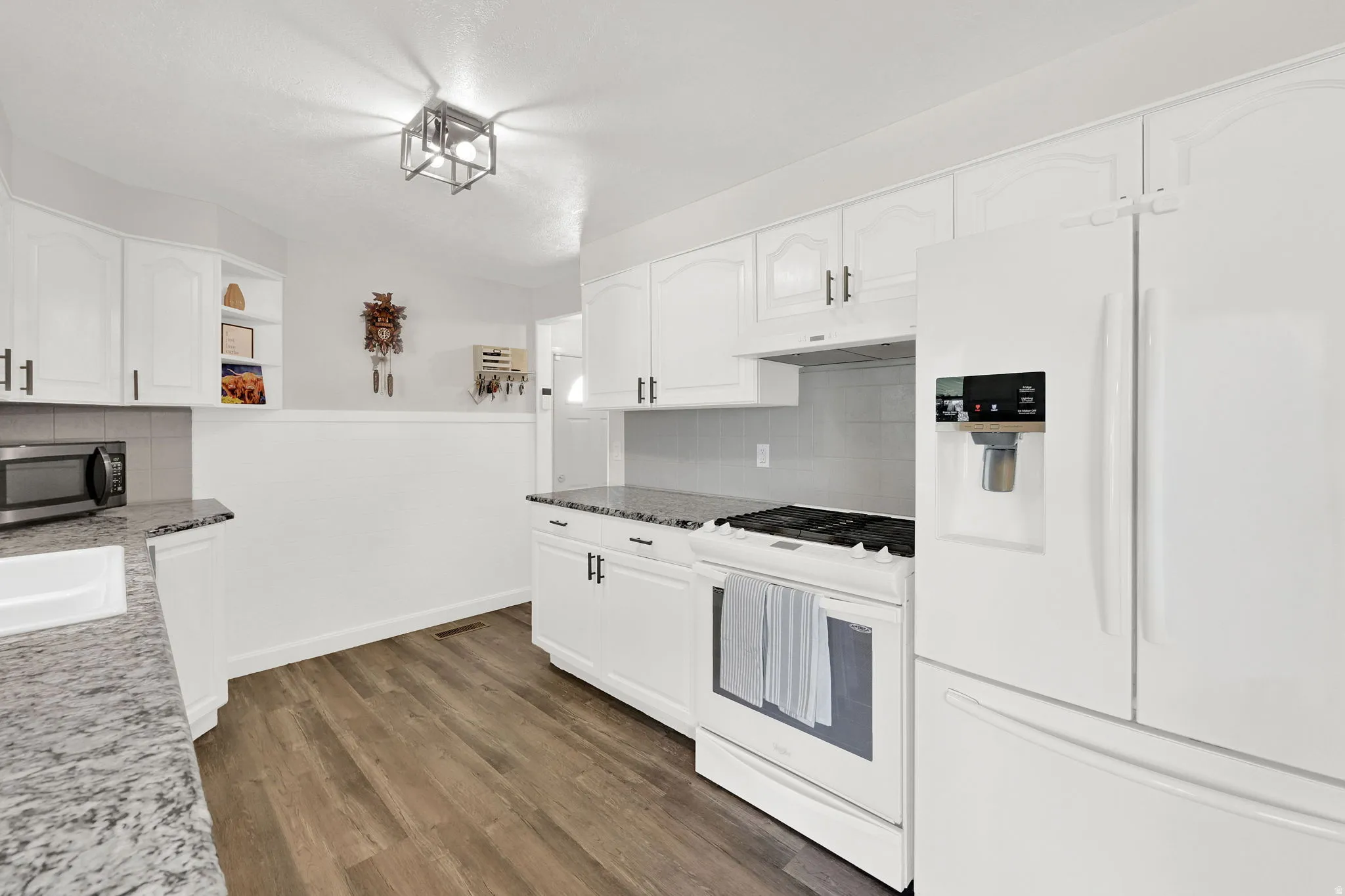 Kitchen with white appliances, dark wood-type flooring, white cabinetry, open shelves, and wainscoting