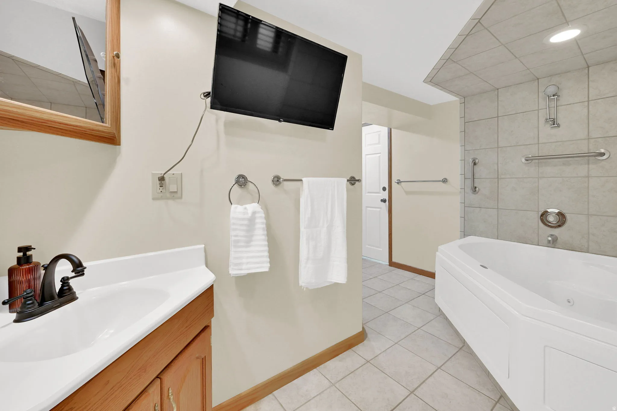 Bathroom with a tub with jets, vanity, light tile patterned floors, recessed lighting, and a shower