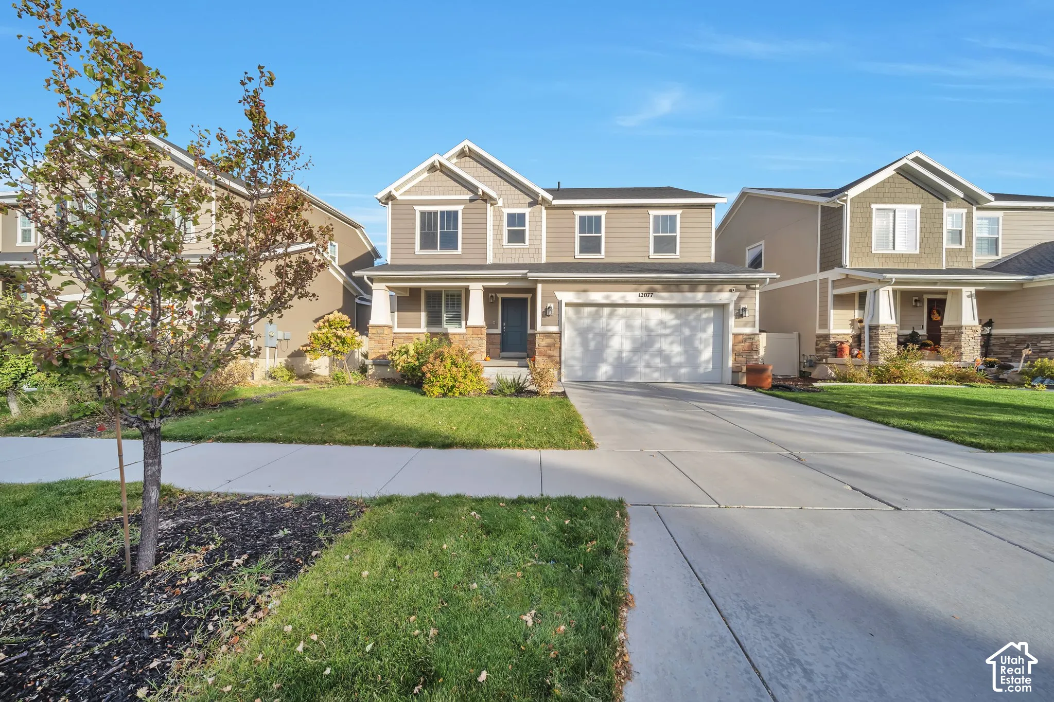 Craftsman inspired home featuring a porch, an attached garage, concrete driveway, stone siding, and a front yard
