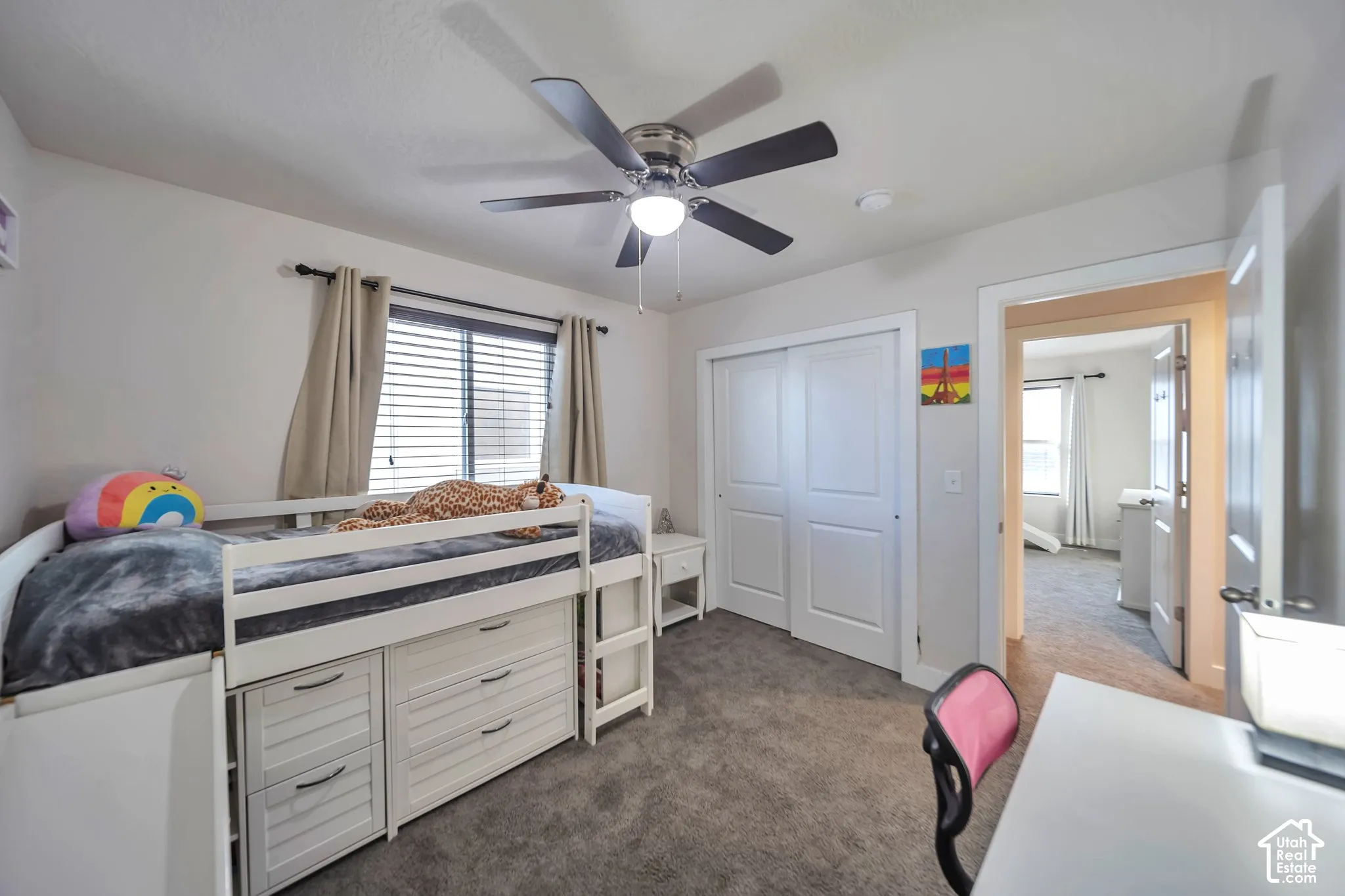 Carpeted bedroom with a ceiling fan