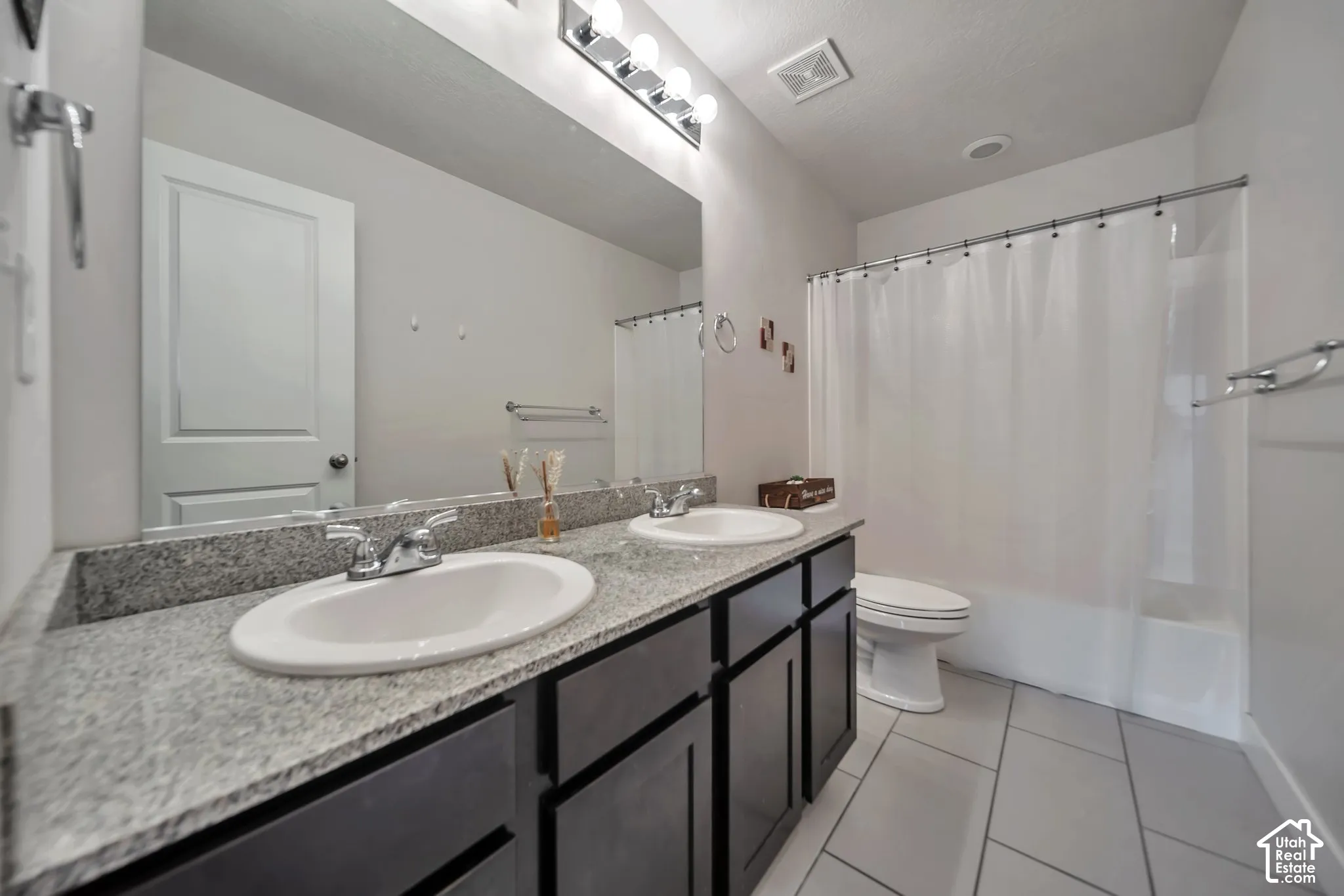 Full bathroom with double vanity, light tile patterned flooring, and shower / bath combo