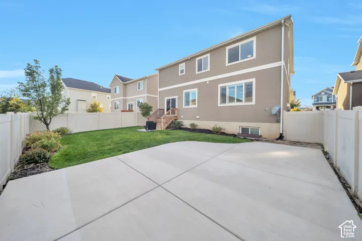 Back of house with a fenced backyard, a large patio area