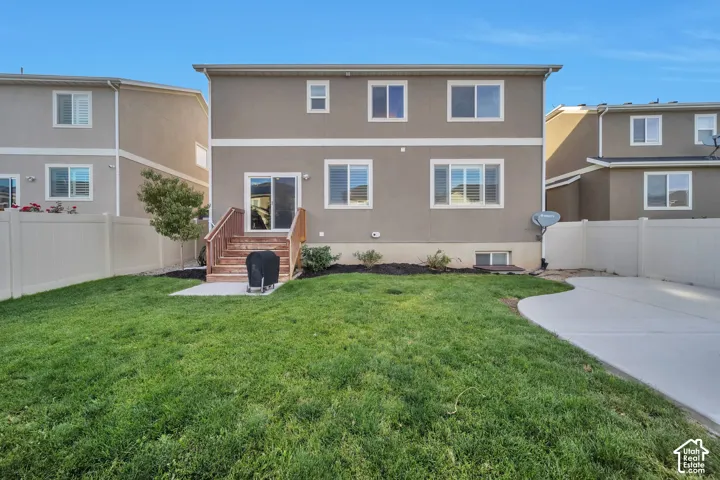 Rear view of house with a fenced backyard and a large patio