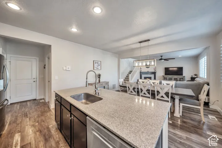 Kitchen with open floor plan, light stone counters, pendant lighting, and stainless steel appliances
