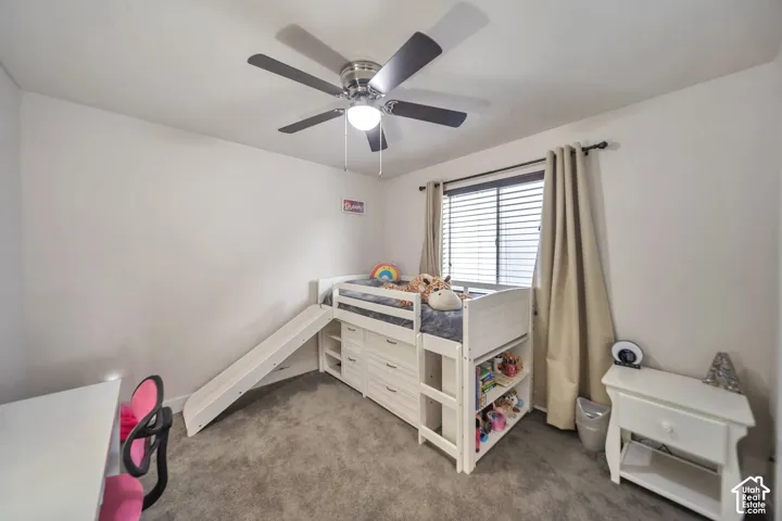 Carpeted bedroom with a ceiling fan