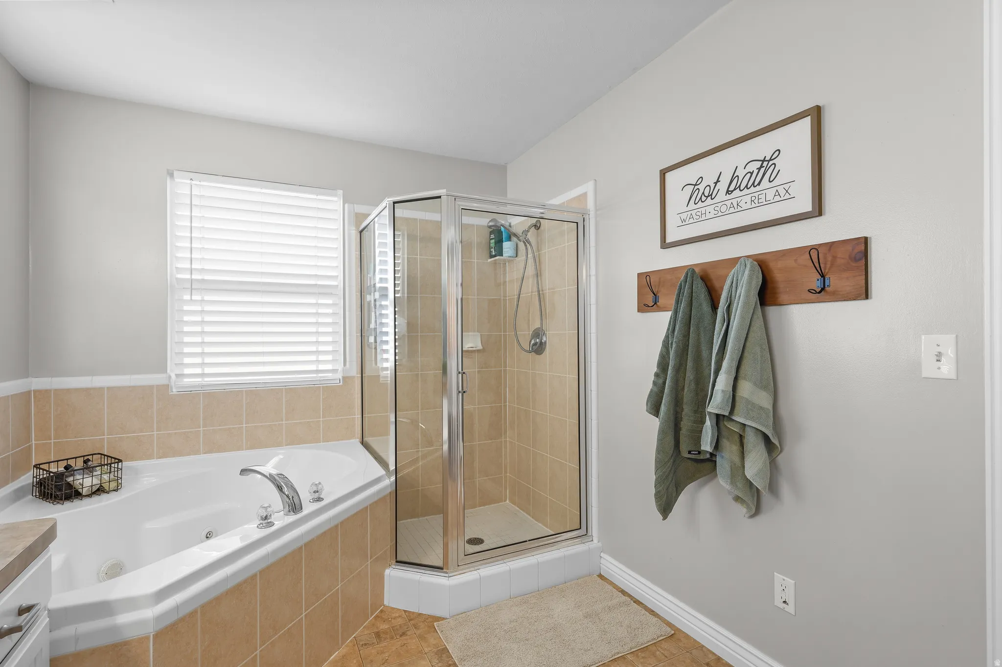 Bathroom featuring a shower stall, a jetted tub, and light tile patterned flooring