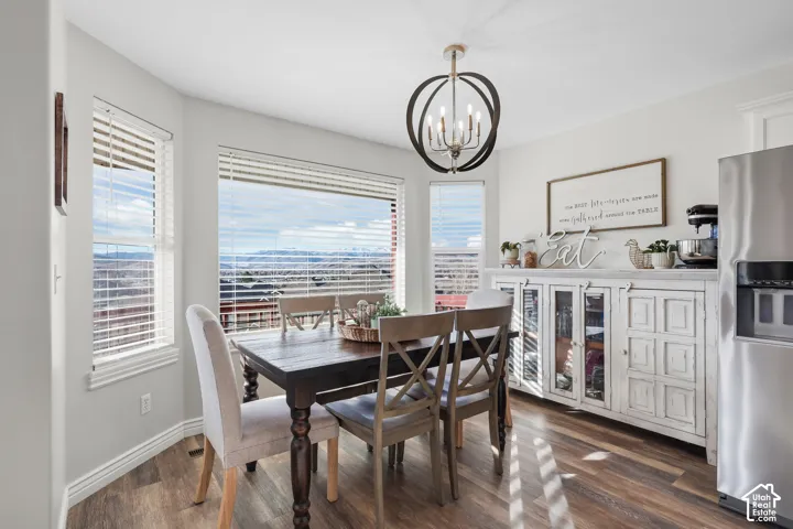 Dining area with dark wood-style floors and hanging lights