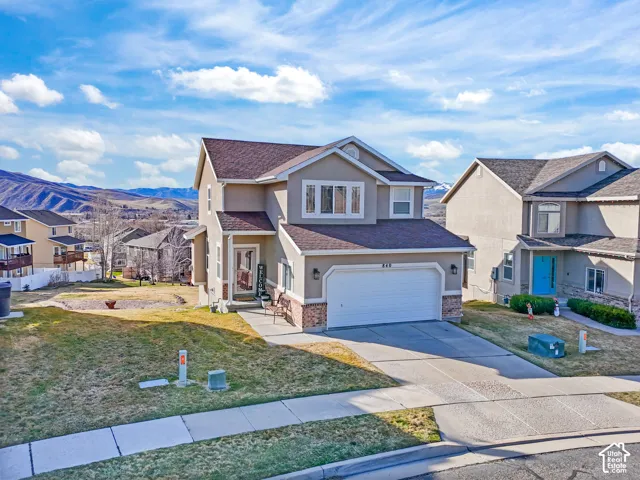 Traditional home with stucco siding, concrete driveway, a residential view, an attached garage, and a front yard