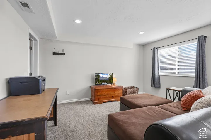 Carpeted living area with recessed lighting and a textured ceiling