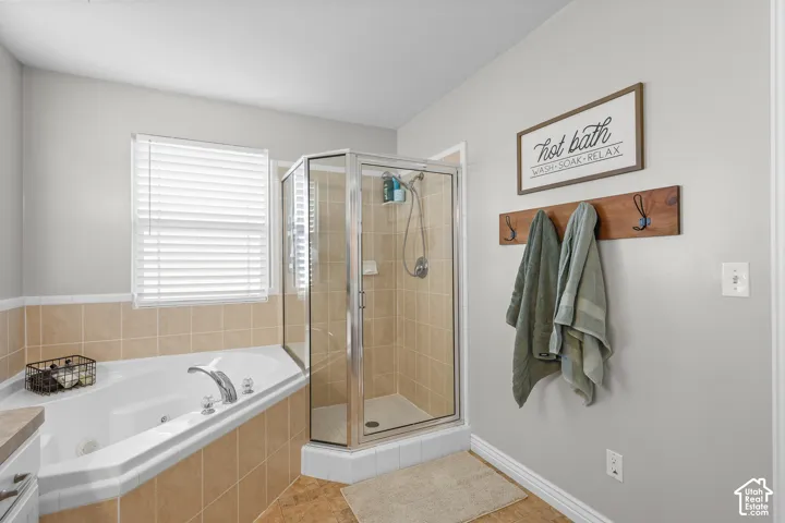 Bathroom featuring a shower stall, a jetted tub, and light tile patterned flooring
