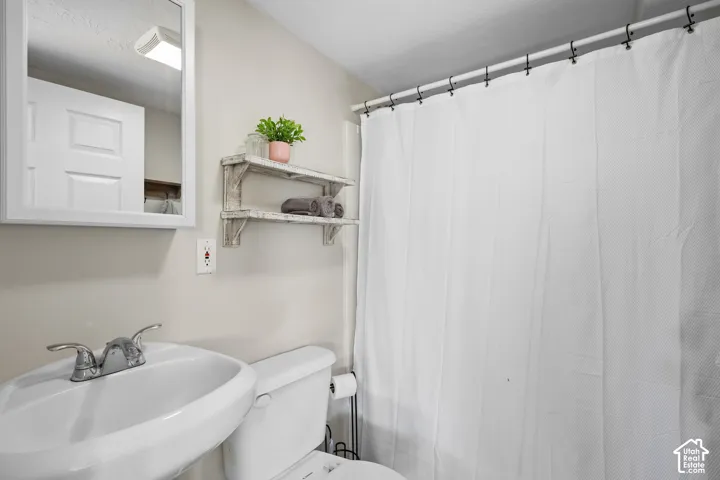 Bathroom featuring toilet and a shower with curtain