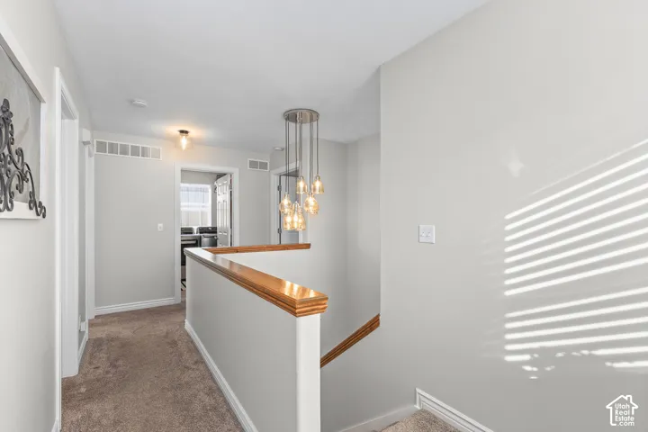 Corridor with an upstairs landing and carpet flooring