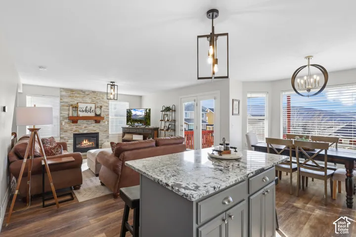 Kitchen featuring light stone counters, dark wood-style flooring, a center island, and a chandelier