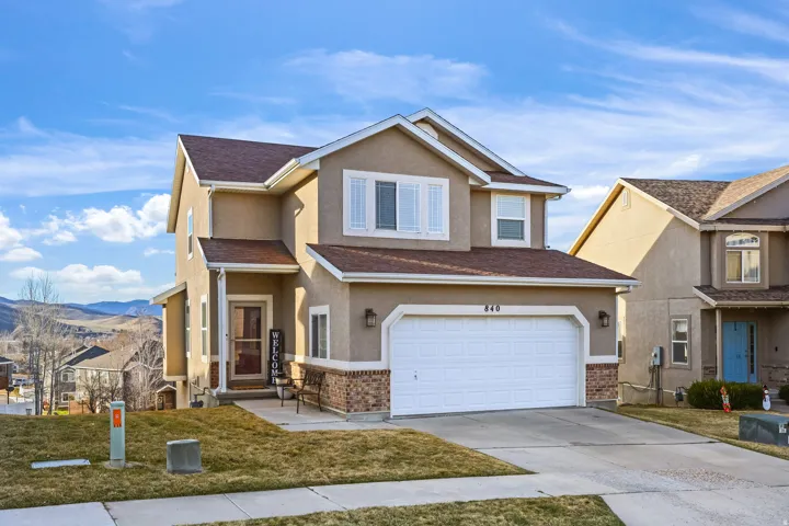 Traditional home featuring a front lawn, stucco siding, concrete driveway, an attached garage, and a mountain view
