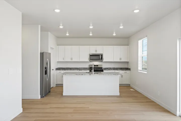 *DISCLAIMER* Interior package and colors may vary.  Kitchen featuring white cabinetry, dark stone countertops, light wood-style floors, an island with sink, and recessed lighting