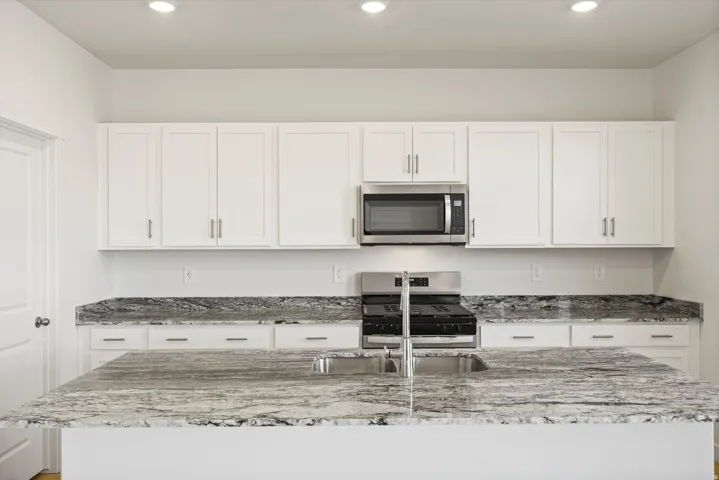 *DISCLAIMER* Interior package and colors may vary.  Kitchen with light stone countertops, white cabinets, stainless steel appliances, a kitchen island with sink, and recessed lighting
