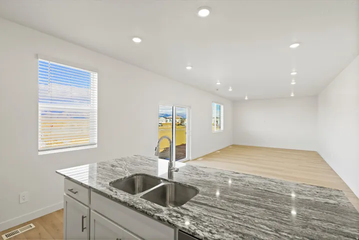 *DISCLAIMER* Interior package and colors may vary.  Kitchen with light wood-type flooring, light stone countertops, open floor plan, recessed lighting, and white cabinets