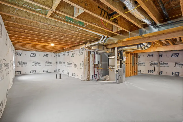 Unfinished basement featuring heating unit and water heater