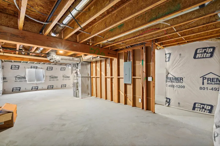 Unfinished basement featuring heating unit and electric panel