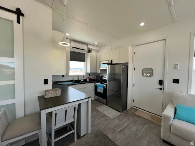 Kitchen featuring dark countertops, stainless steel appliances, dark wood finished floors, a barn door, and white cabinets