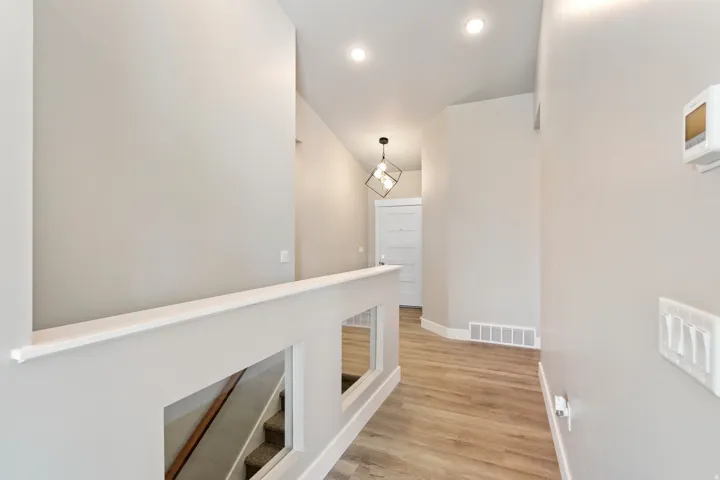 Corridor with light wood-type flooring and an upstairs landing