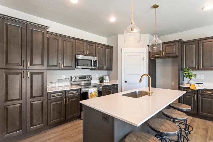 Kitchen with dark wood finish cabinetry, stainless steel appliances, and a kitchen island with sink