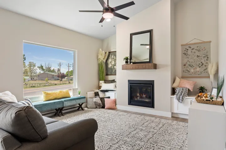 Living room featuring a glass covered fireplace, wood finished floors, a ceiling fan, and vaulted ceiling