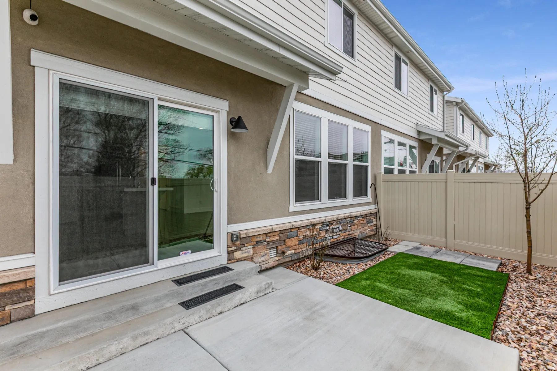 View of exterior entry with stone siding, stucco siding, and a patio area