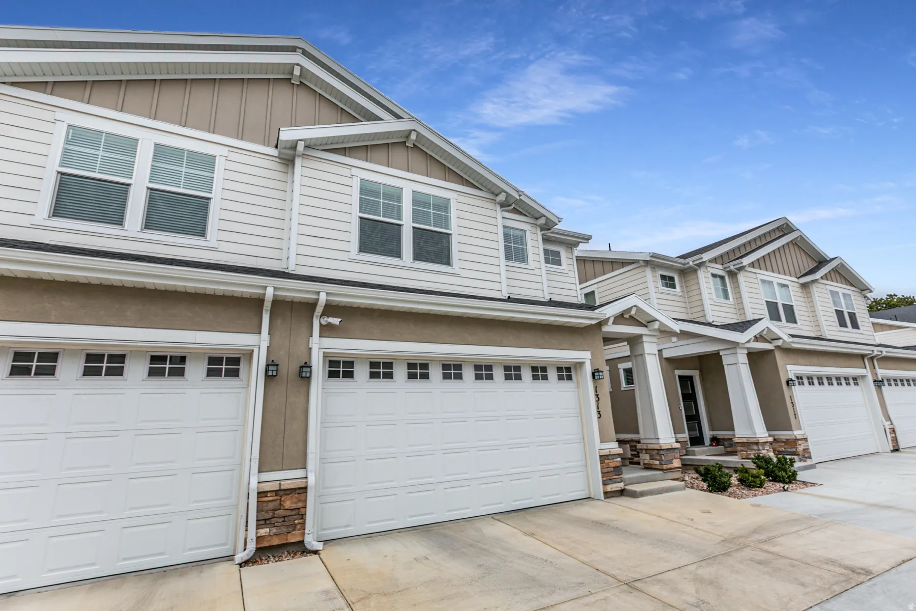 Craftsman inspired home with board and batten siding, stone siding, a garage, and concrete driveway