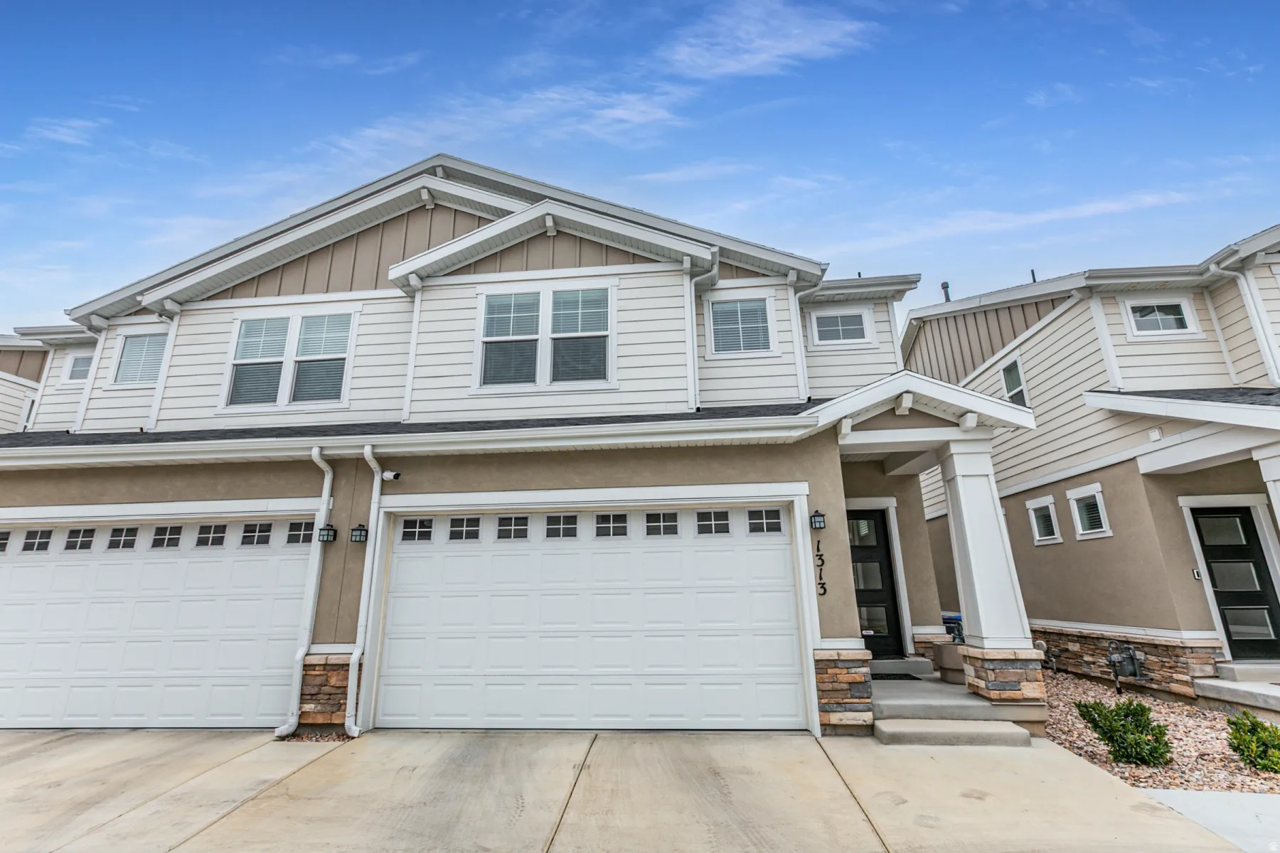 Craftsman house featuring stone siding, concrete driveway, an attached garage, and board and batten siding