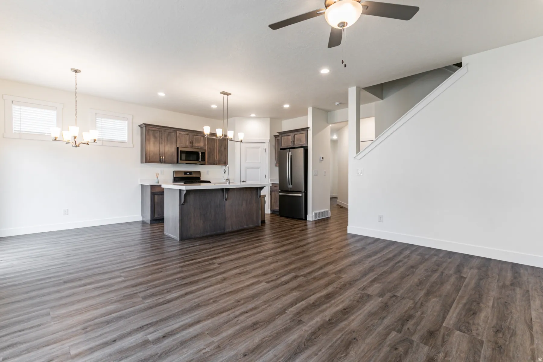 Kitchen featuring suspended lighting, open floor plan, light countertops, and stainless steel appliances