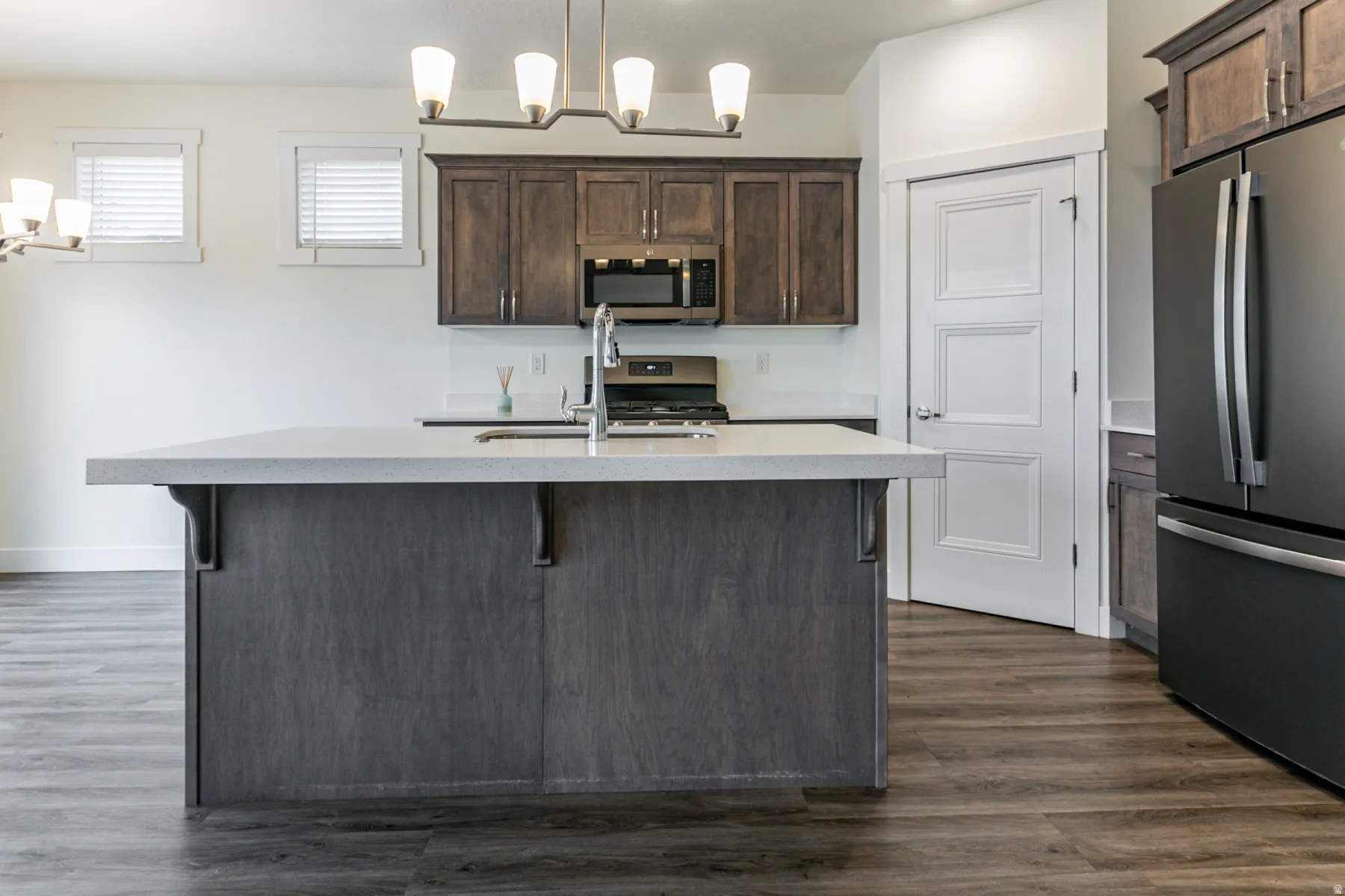 Kitchen featuring stainless steel appliances, dark wood finish cabinetry, a breakfast bar area, and dark wood-style floors