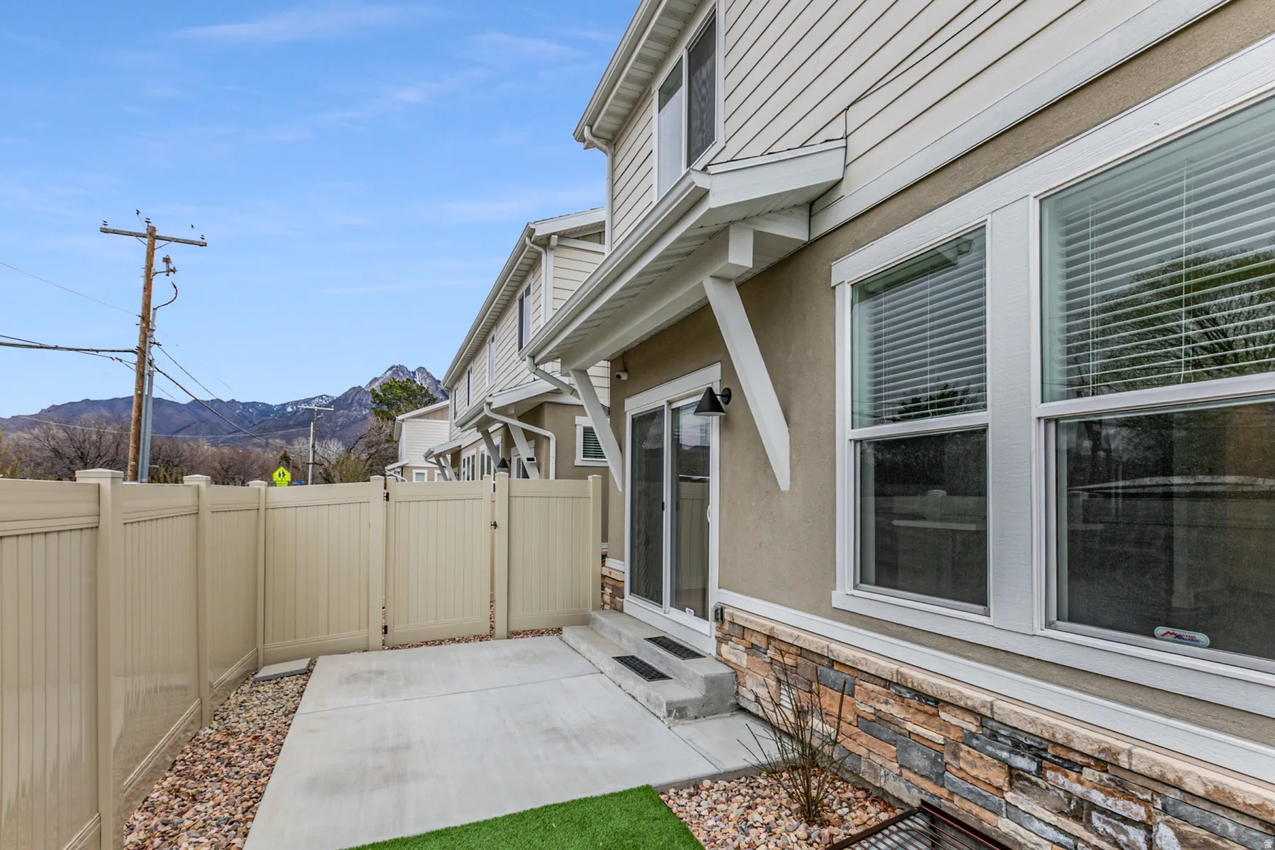 Fenced backyard with a mountain view, a gate, entry steps, and a patio