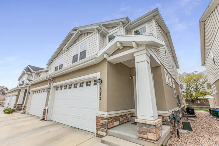 Craftsman-style home with a garage, stucco siding, driveway, and stone siding