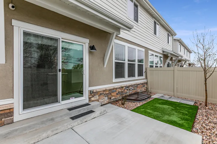 View of exterior entry with stone siding, stucco siding, and a patio area