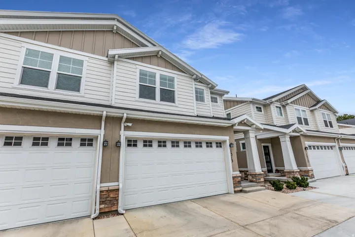 Craftsman inspired home with board and batten siding, stone siding, a garage, and concrete driveway