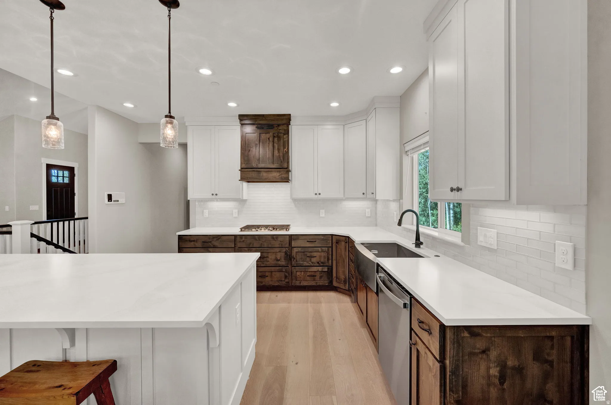 Dual tone kitchen with dual tone cabinetry, a kitchen bar, light wood-type flooring, decorative light fixtures, and stainless steel appliances