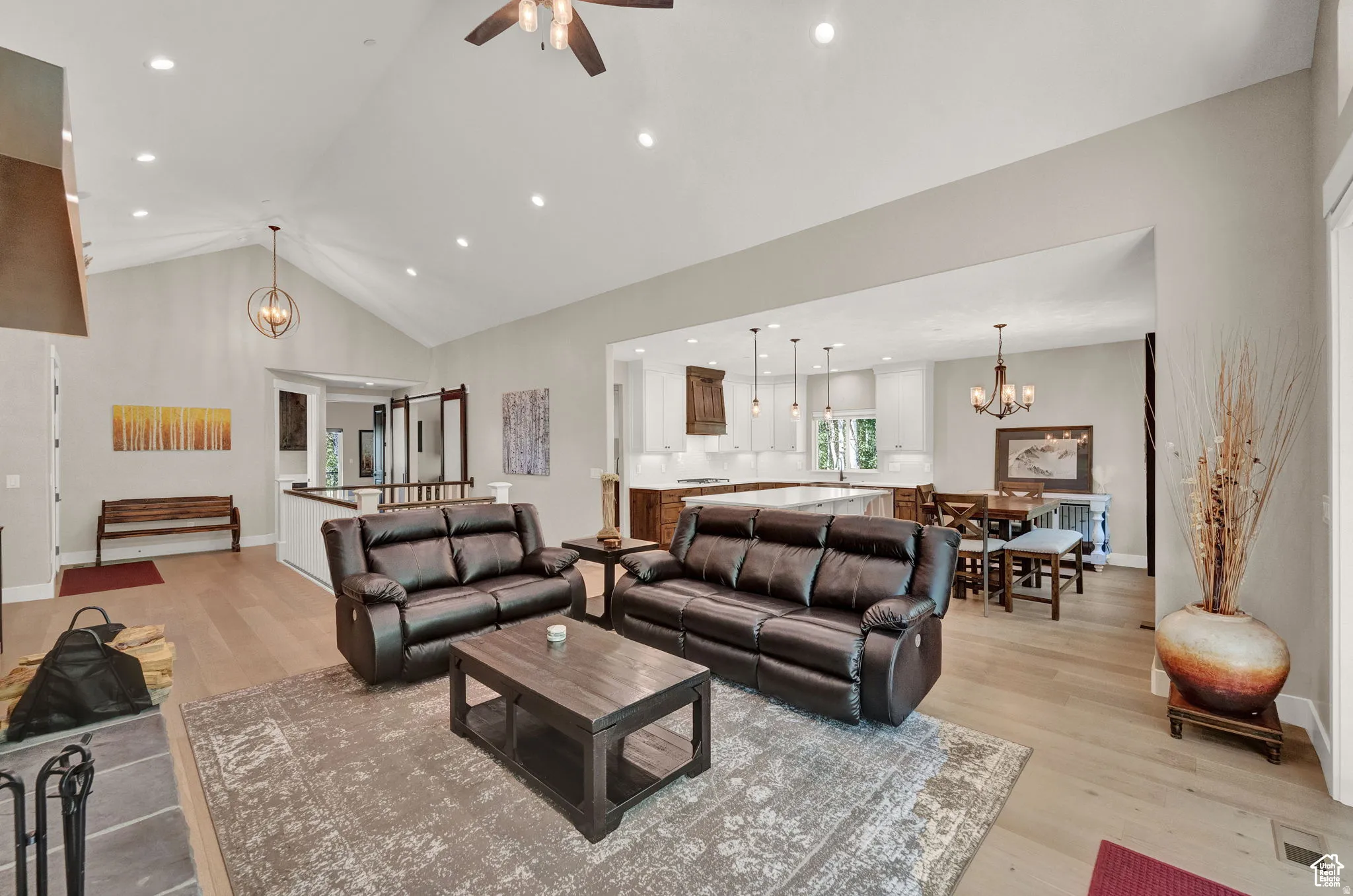 Living room with a chandelier, light wood-style floors, a high ceiling, and ceiling fan
