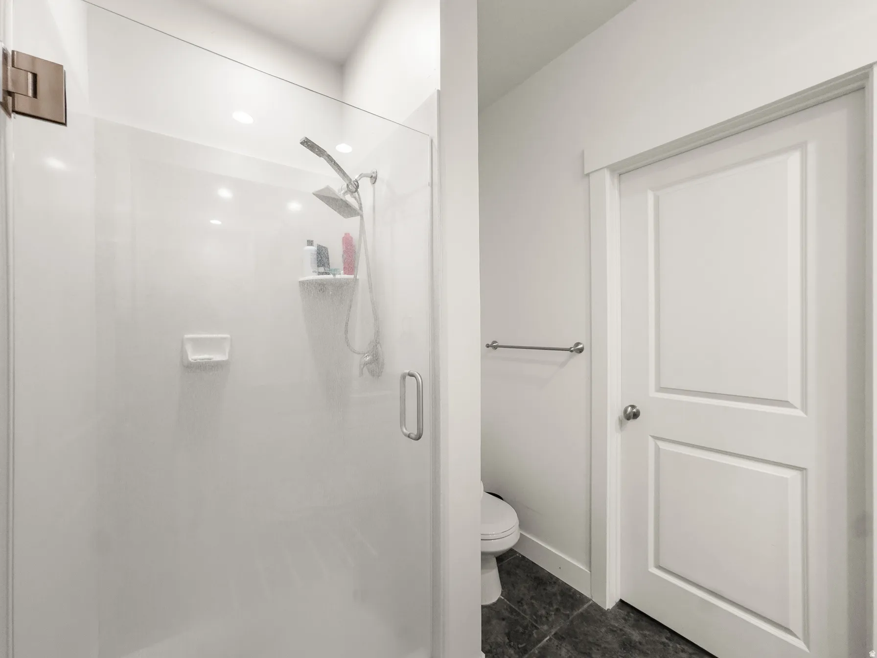Bathroom with a stall shower and dark tile patterned floors