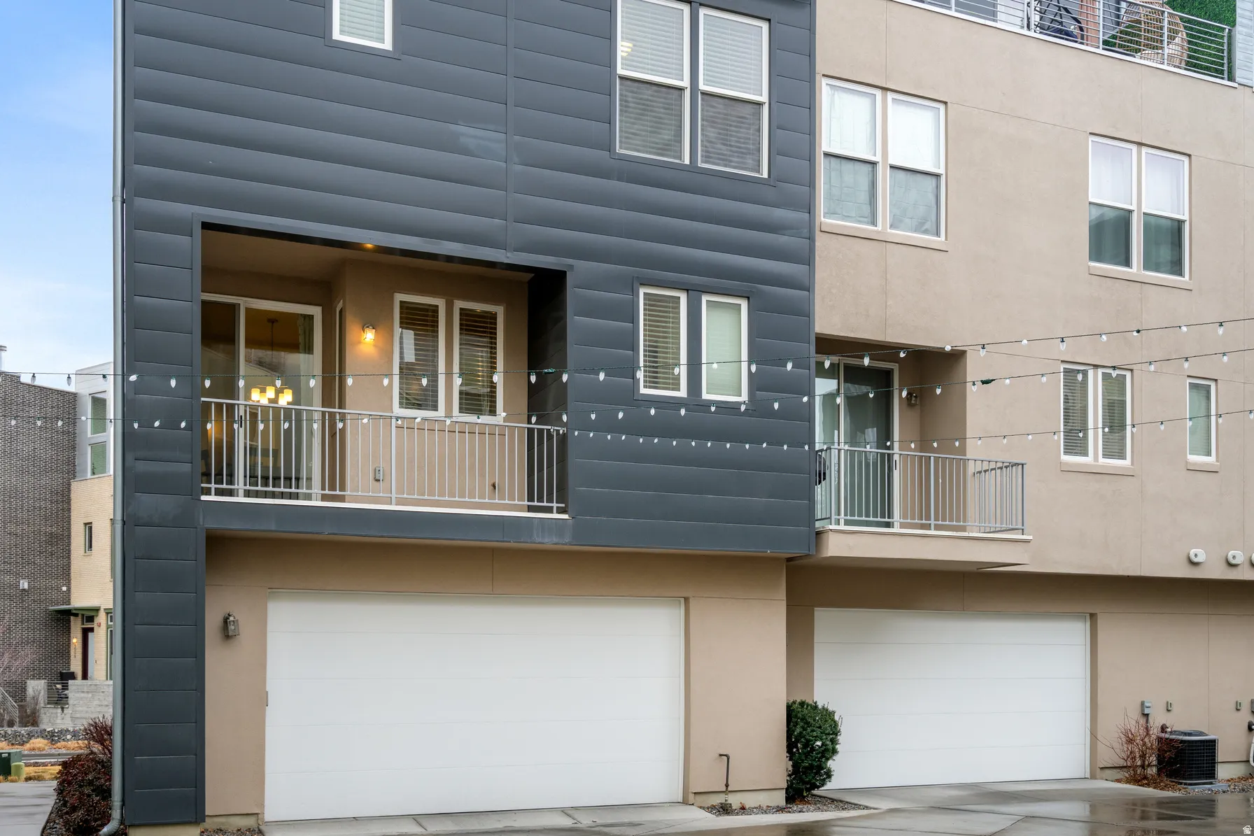 Back of house featuring a balcony, an attached garage, stucco siding, and concrete driveway
