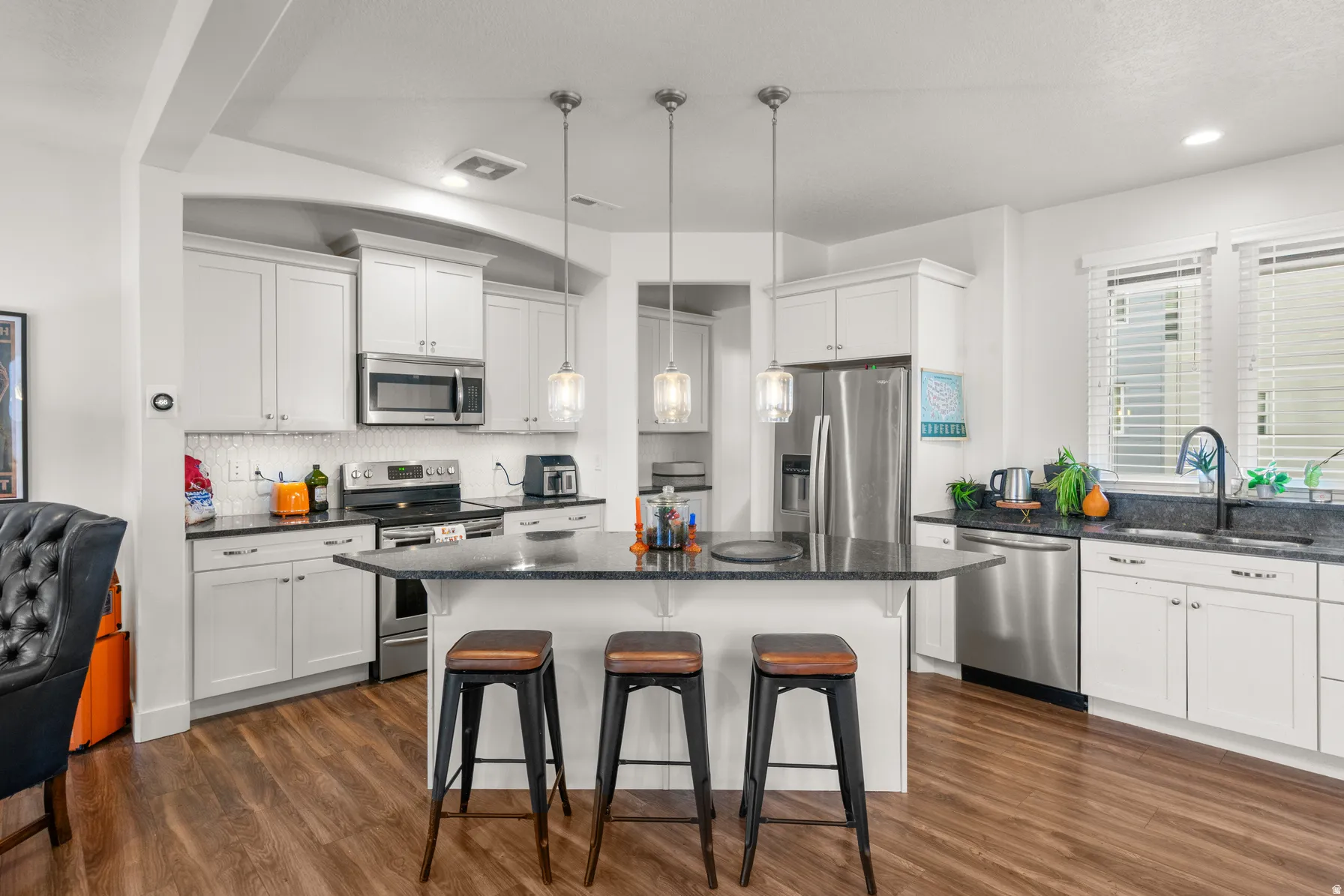 Kitchen featuring a kitchen bar, stainless steel appliances, a center island, and white cabinets