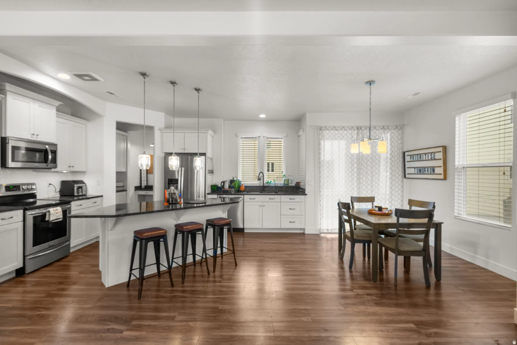 Kitchen featuring stainless steel appliances, a kitchen breakfast bar, white cabinets, and a center island