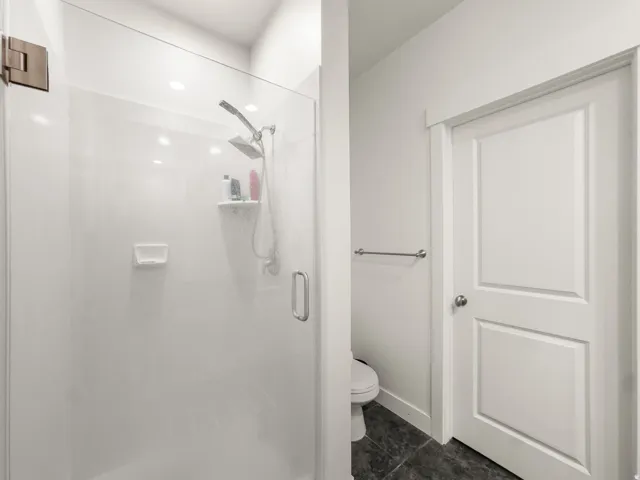 Bathroom with a stall shower and dark tile patterned floors