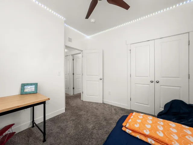 Bedroom featuring dark colored carpet, a ceiling fan, and a closet