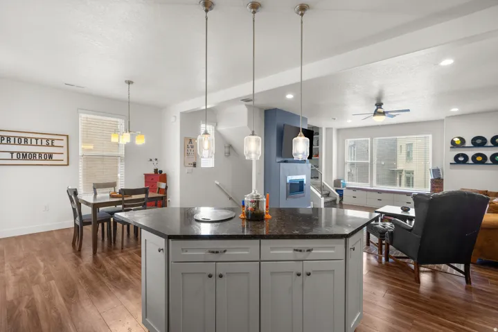 Kitchen featuring open floor plan, gray cabinetry, a kitchen island, dark wood finished floors, and a textured ceiling