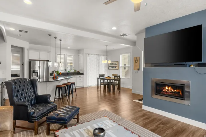 Living room featuring dark wood finished floors, a glass covered fireplace, a ceiling fan, and recessed lighting