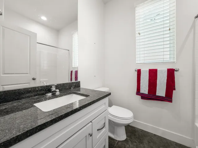 Bathroom featuring vanity, dark tile patterned floors, and tub / shower combination