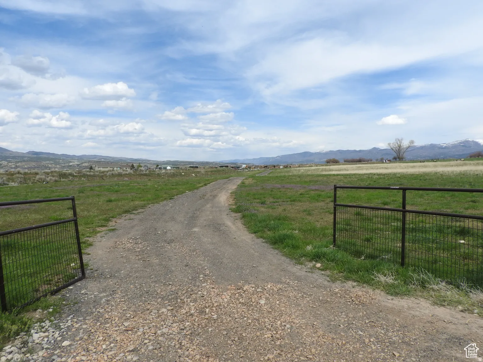 View of road with a mountain view, a view of rural / pastoral area, and a gated entry