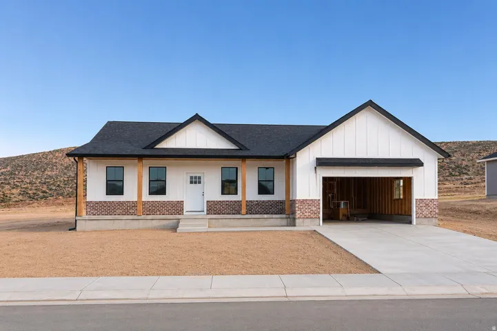 Contemporary ranch-style exterior featuring vertical white siding, brick accents, dark shingle roofing, and a single-car garage