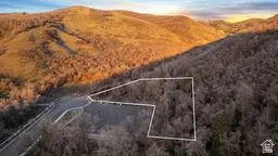 Aerial view of property and surrounding area with property parcel outlined and a mountainous background